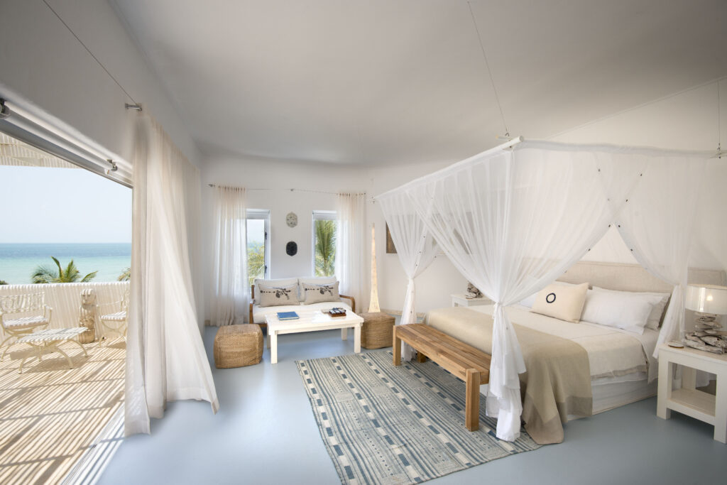 White beachfront suite with canopy bed and ocean view