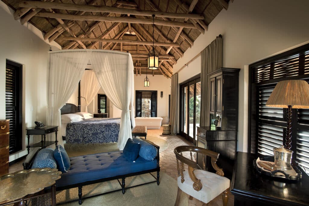 Luxury suite interior with thatched roof and four-poster bed at Casinha Villa